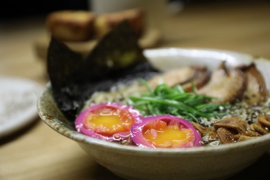 Photo of Bowl of ramen noodles with eggs, wakame salad and sesame seeds on table, closeup