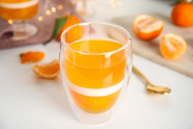 Delicious tangerine jelly in glass on white table, closeup