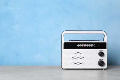 Retro radio receiver on grey table against light blue background. Space for text