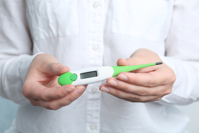 Photo of Woman holding modern digital thermometer, closeup view