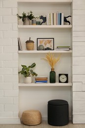 Photo of Beautiful green plants and different decor on shelves in room. Interior design