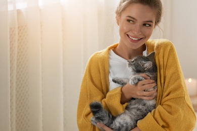 Young woman with cute cat at home. Cozy winter
