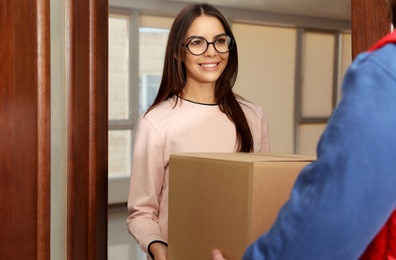 Woman receiving parcel from delivery service courier indoors
