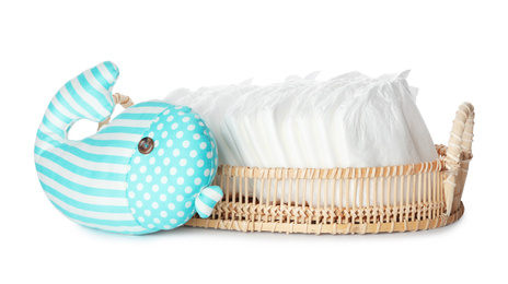 Wicker tray with disposable diapers and toy on white background