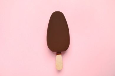 Photo of Ice cream glazed in chocolate on pink background, top view