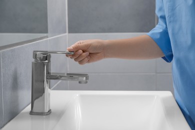 Doctor opening tap water in bathroom, closeup