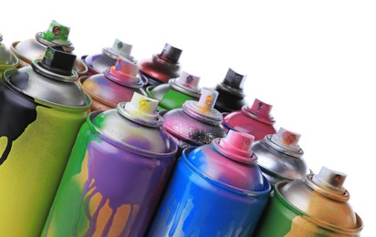 Used cans of spray paints on white background, closeup. Graffiti supplies