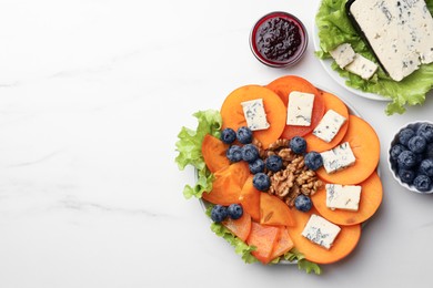 Photo of Delicious persimmon with blue cheese on white marble table, flat lay. Space for text