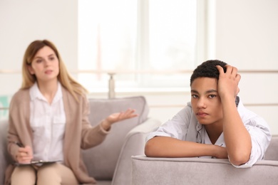 Young female psychologist working with teenage boy in office