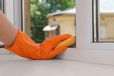 Photo of Young woman cleaning window frame with rag at home, closeup