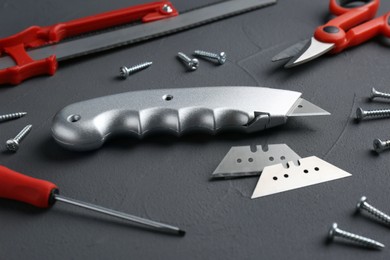 Utility knife with blades among other tools on grey background