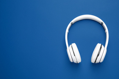 Headphones on bright background, top view with space for text. Color of the year 2020 (Classic blue)
