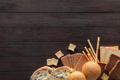 Photo of Food photography. Delicious bread slices and different bakery products on black wooden table, flat lay with space for text