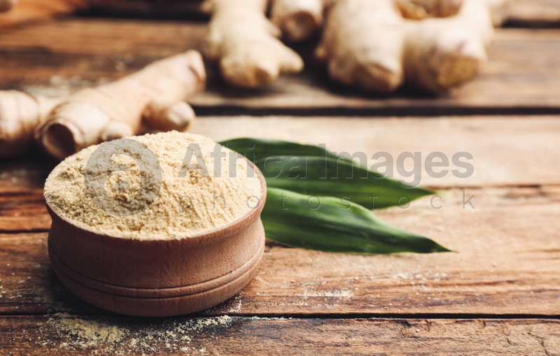 Dry ginger powder, fresh root and leaves on wooden table. Space for text