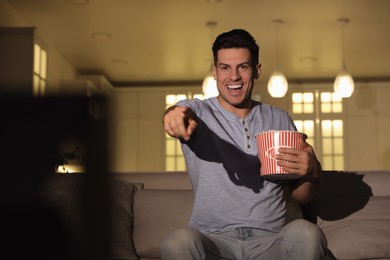 Man watching movie with popcorn on sofa at night