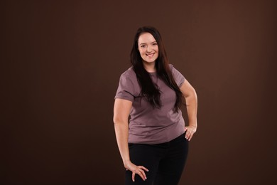 Beautiful overweight woman with charming smile on brown background