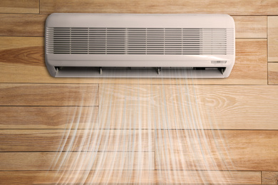 Modern air conditioner on wooden wall indoors