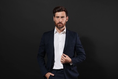 Photo of Portrait of handsome bearded man in suit on black background