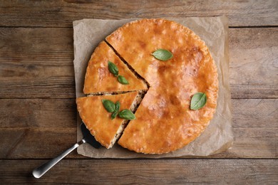 Delicious pie with meat and basil on wooden table, top view