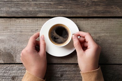 Photo of Woman with cup of hot aromatic coffee at wooden table, top view