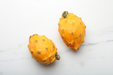 Photo of Delicious yellow pitahaya fruits on white marble table, flay lay