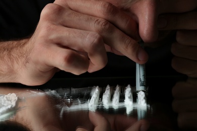 Drug addict taking cocaine at table, closeup view