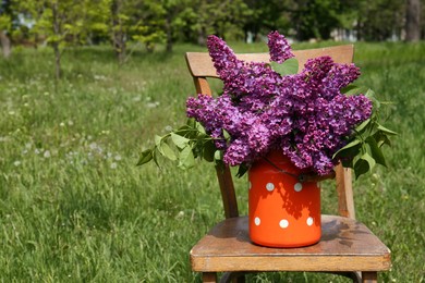 Beautiful lilac flowers in milk can outdoors. Space for text