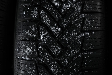 Snowy winter tire on black background, closeup