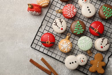 Beautifully decorated Christmas macarons and cinnamon on light grey table, flat lay