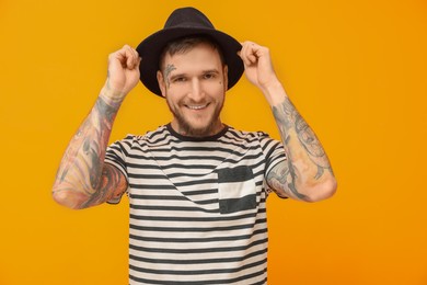 Photo of Portrait of handsome hipster man wearing stylish hat on orange background