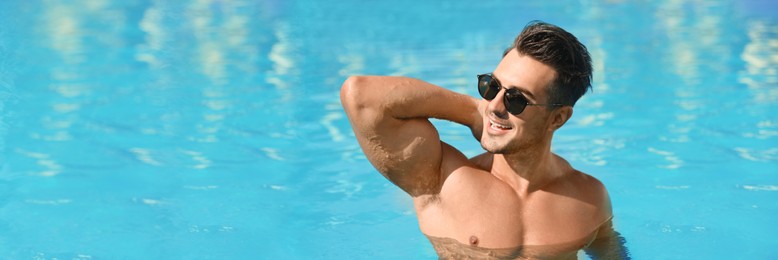 Handsome man in swimming pool on sunny day, space for text. Banner design