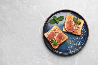Tasty toasts with fig pieces, peanut butter and walnuts on light grey marble table, top view. Space for text