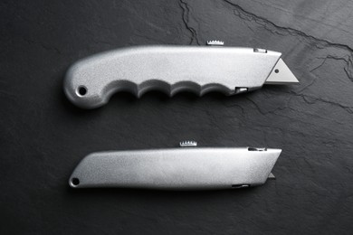 Photo of Two utility knives on black table, flat lay