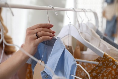 Woman choosing dress to buy in showroom, closeup