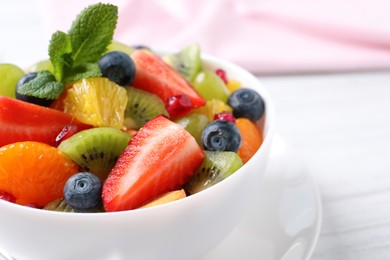 Delicious fresh fruit salad in bowl on table, closeup. Space for text
