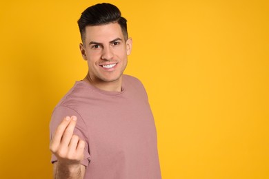 Handsome man snapping fingers on yellow background. Space for text