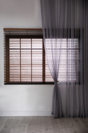 Window with beautiful curtain and blinds in empty room