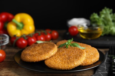 Delicious fried breaded cutlets with basil on wooden table, closeup