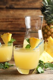 Photo of Delicious fresh pineapple juice with mint on wooden table