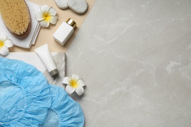 Flat lay composition with shower caps and toiletries on color background. Space for text