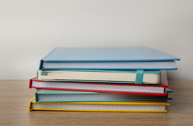 Stack of colorful planners on wooden table, closeup