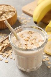 Glass of tasty banana smoothie with oatmeal on light grey table