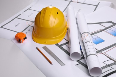 Construction drawings, safety hat, tape measure, pencil and ruler on white background