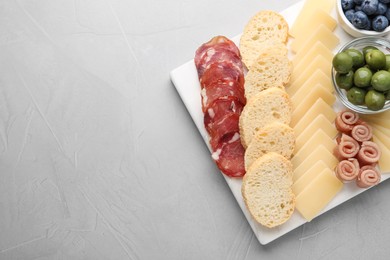 Tasty parmesan cheese and other different appetizers on white table, top view. Space for text