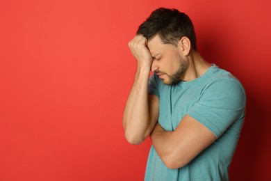 Man suffering from terrible migraine on red background. Space for text