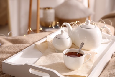 White tray with ceramic tea set on bed