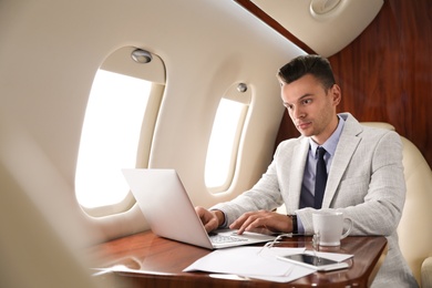 Photo of Young man working with laptop on plane. Comfortable flight