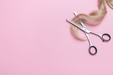 Professional hairdresser thinning scissors and hair strand on pink background, flat lay with space for text. Haircut tool