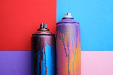 Used cans of spray paints on color background, flat lay. Graffiti supplies