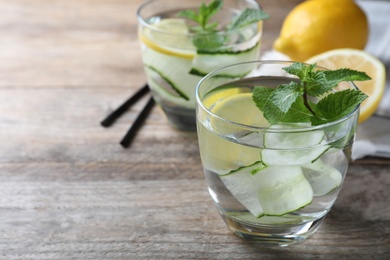 Photo of Refreshing water with cucumber, lemon and mint on wooden table, closeup. Space for text